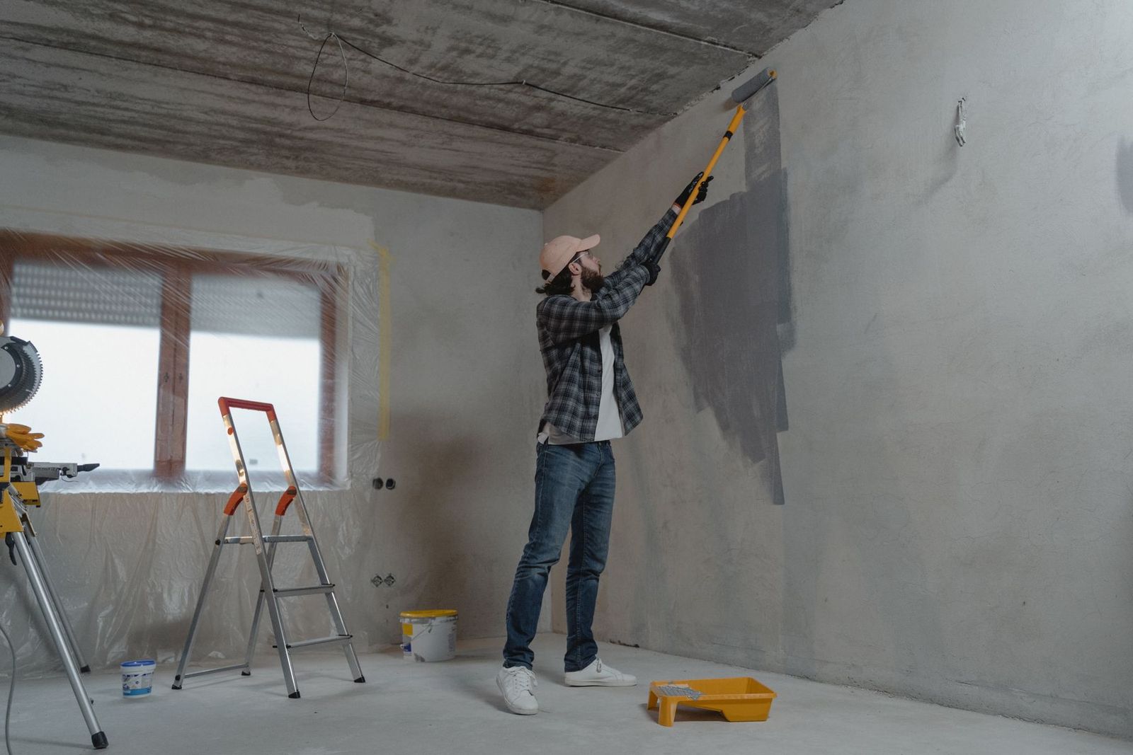 Maler streicht eine Innenwand mit der Rolle